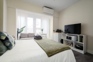 sypialnia z białym łóżkiem z telewizorem w obiekcie Beach Studio Apartment Playa Malagueta w Maladze