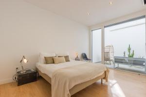 a white bedroom with a bed and a large window at Lemon Tree Home in Sesimbra +23 photos