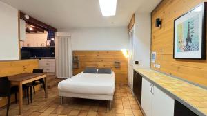 a room with a bed and a table and a kitchen at Villa Liberté in Villejuif