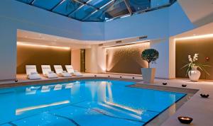 a swimming pool in a hotel with chairs and a plant at Porto Platanias Beach Resort & Spa in Plataniás