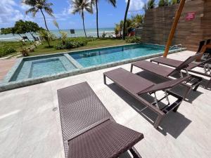a swimming pool with two chairs and a table at Kauai Beach residence in Tamandaré