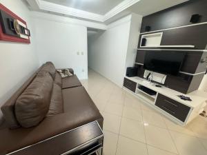 a living room with a brown couch and a television at Apartamento Almeida e Moraes 3 Suítes com Hidro in Itapema