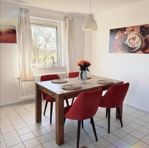 a dining room with a table and red chairs at Maries Sterntaler Appartement in Schillig