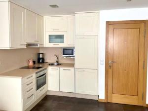 a white kitchen with white cabinets and a door at Arnela in Baiona
