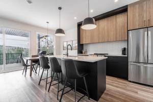a kitchen with a large island with bar stools at Le Raffine hot tub River Front in Saint Come