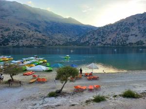 a group of chairs and umbrellas on the shore of a lake at Abelia Abode Apt in Kavros