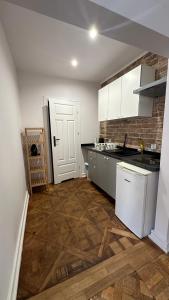 a kitchen with white cabinets and a wooden floor at Kamienica Śródmieście Apartament 18A in Warsaw