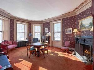 a living room with a table and a fireplace at Elmwood Heritage Inn in Charlottetown