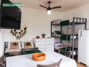 a room with bunk beds and a table and a tv at Casa Quintal - Pé na Areia - Araçatiba Ilha Grande in Praia de Araçatiba