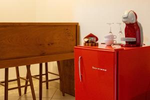 a red refrigerator next to a table with a bottle of syrup at Apartamento Le Quatre Avenida in Monte Verde