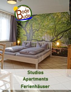 a bedroom with a bed with a tree mural at BodeBude in Thale