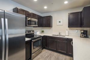 Una cocina con gabinetes de madera y un refrigerador de acero inoxidable. en 6G Moab RedCliff Condo POOL & HOT TUB, en Moab
