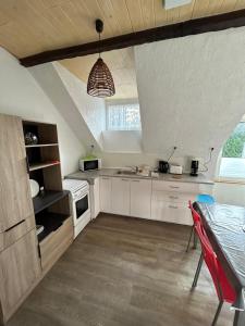 a kitchen with white cabinets and a table with a red chair at Appartement 2 chambres proche des plages pour 6 personnes in Pont-lʼAbbé