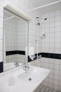 La salle de bains blanche est pourvue d'un lavabo et d'un miroir. dans l'établissement Fjordslottet Hotel, à Fotlandsvåg
