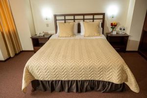 a hotel room with a large bed and two tables at Hotel San Sebastián Loja in Loja