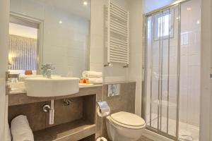 uma casa de banho com um WC, um lavatório e um chuveiro em Hôtel Mondial em Paris