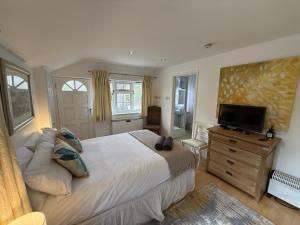 a bedroom with a large bed and a flat screen tv at The Guesthouse Hideaway by Newfo.rest in Hordle