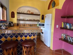a kitchen with a bar with a white refrigerator at Luna - Casa MoJo's delightful 1BR, kitchen, pool in Sayulita