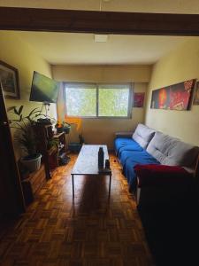 a living room with a blue couch and a table at Habitación en apartamento en Parque Battle Montevideo in Montevideo