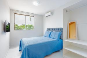 a bedroom with a blue bed and a window at IT99 Lindo Apto 3/4 Pé na Areia - Itacimirim in Camacari +21 photos