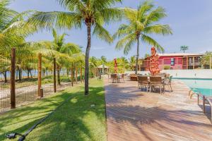 a resort with a pool and tables and palm trees at IT99 Lindo Apto 3/4 Pé na Areia - Itacimirim in Camacari
