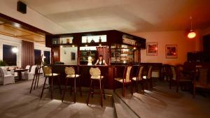a bar with chairs and a woman sitting at it at Barbarossa Hotel Kelbra in Kelbra