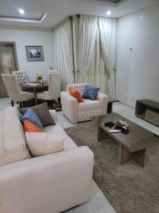 Una sala de estar con dos sofás blancos y una mesa. en Outstand-Chouette Luxury Apartment, en Abuja