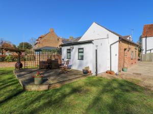 a backyard with a wooden deck in the grass at The Old Dairy in Herne Bay
