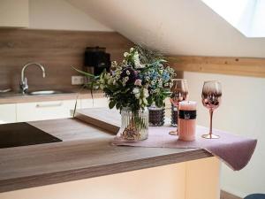 普夫龙滕Ferienwohnung Kuschelnest - Haus Alpentenne, Pfronten的一张桌子,上面放着两杯酒,花瓶上放着鲜花