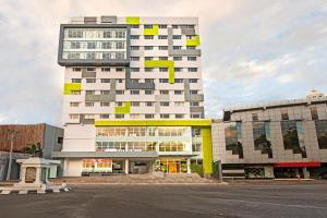 a tall building with yellow and white at Whiz Prime Hotel Hasanuddin Makassar in Makassar