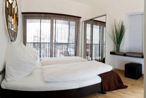 a bedroom with a white bed with a large window at Arnsteiner Apartments in Zell am See