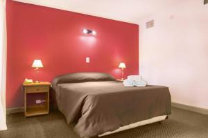 a bedroom with a red wall and a bed at Hotel Royal in Neuquén