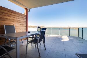 a table and chairs on a balcony with a view of the water at LAGOVIDA Kapitänskajüte e am Störmthaler See in Großpösna