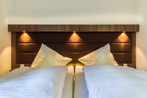 a bed with white pillows and a brown headboard at LAGOVIDA Hafenhaus d am Störmthaler See in Großpösna