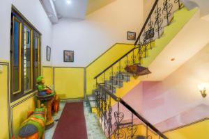 a hallway with a staircase with yellow and green walls at Super Hotel O Sikar Road Jaipur Formerly Garg Niwas in Jaipur