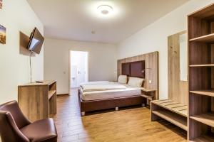 a bedroom with a bed and a chair and a television at LAGOVIDA Möwenblick c am Störmthaler See in Großpösna