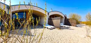 a house on the beach with two chairs in front of it at LAGOVIDA Dünenhaus Comfort Familia c am Störmthaler See in Großpösna