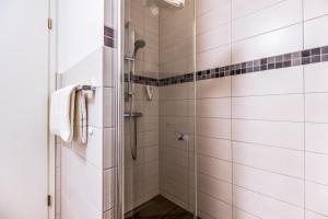 a shower in a bathroom with white tiles at LAGOVIDA Piratennest a am Störmthaler See in Großpösna
