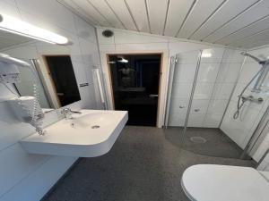 a white bathroom with a sink and a shower at Family-friendly cottage in Kinsarvik in Kinsarvik