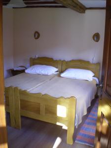 um quarto com uma cama de madeira e 2 almofadas em Apartments Iža Na Trem em Čigoč