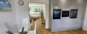 a kitchen with white cabinets and a clock on a wall at 4 Bed 3 Bath Dryer Sky TV & Netflix Free Parking Rear Garden Prime Location in Willen