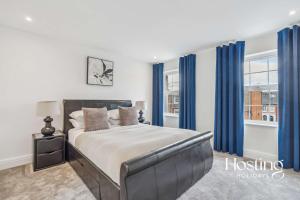 a bedroom with a large bed with blue curtains at Queens Mews Brand New Luxury Home with Parking in Henley on Thames