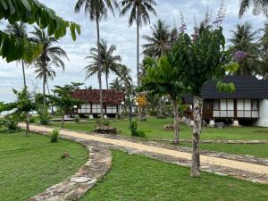 a house with palm trees in front of it at Arys Lagoon Bungalow & Hotel in Karimunjawa