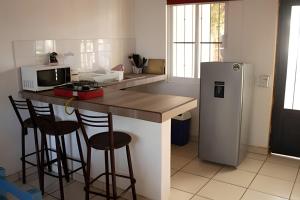 a kitchen with a counter with stools and a refrigerator at C3 Alberca privada a 5 min de la playa y manglar! in La Peñita de Jaltemba