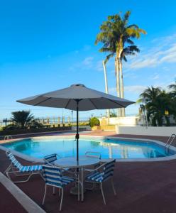 a table and chairs with an umbrella next to a pool at Acogedor Apartamento de playa en Los Corales - La Guaira in Caraballeda