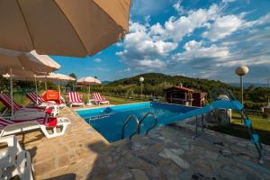 a swimming pool with chairs and an umbrella at Hacienda Antioquia in Berane