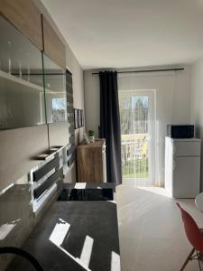 a living room with a large window and a kitchen at 3 Barát Apartman in Kehidakustány