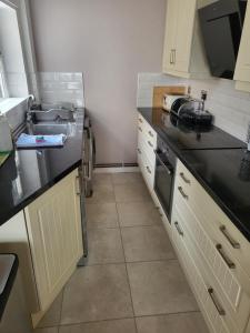 ラグビーにあるRugby town centre house close to rugby train station and rugby schoolのキッチン(黒いカウンタートップ、シンク付)