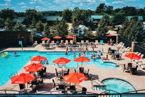 an outdoor swimming pool with red umbrellas and people in it at Edge-O-Dells Resort in Wisconsin Dells