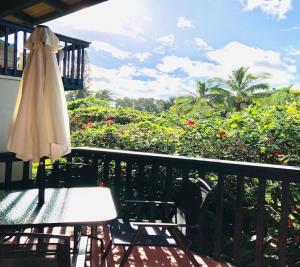プリンスビルにあるPrinceville Townhouse Apt - Views, Pool, Near Hanalei!の傘とテーブルと椅子のあるパティオ